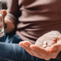 Mężczyzna bierze tabletki z kwasem foliowym i szklankę wody. Dba o swoje zdrowie.